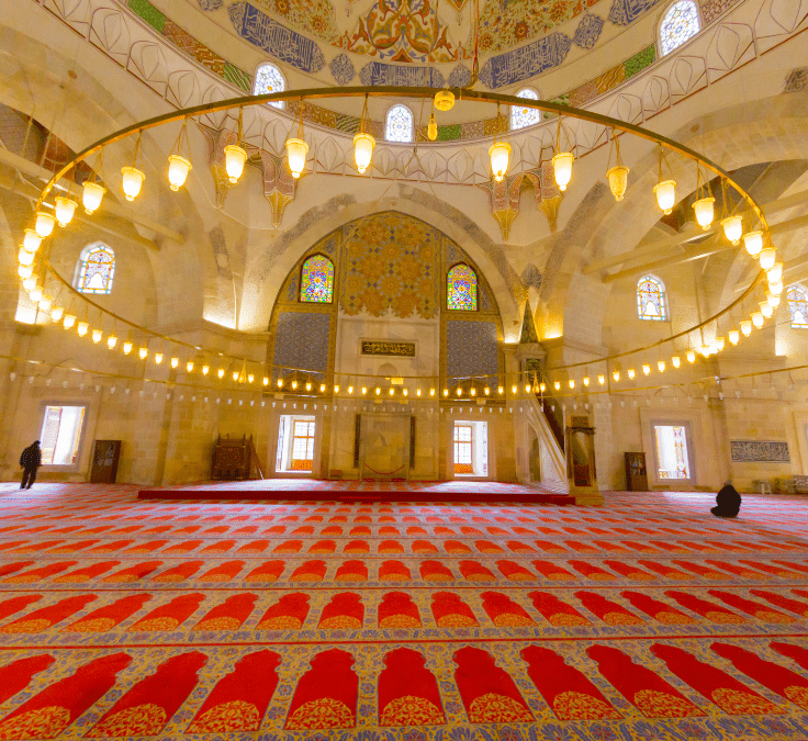 Interior de una mezquita con gran lámpara y alfombra roja representando unidad espiritual